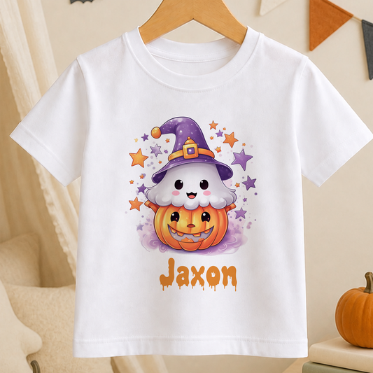 A white t-shirt with a cartoon image of a ghost wearing a witch's hat and a pumpkin, surrounded by stars and a pumpkin. The name "Jaxon" is written below the image.