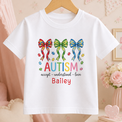 White t-shirt printed with a rainbow autism awareness puzzle-piece ribbon and the words "Accept, Understand, Love", personalised with a name