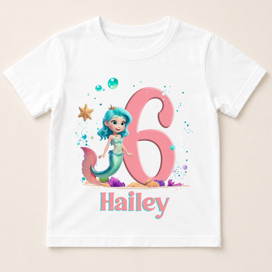 A white t-shirt with a mermaid character and the number 6 printed on it, along with bubbles and a starfish. The text "Hailey" is also printed below the mermaid character.