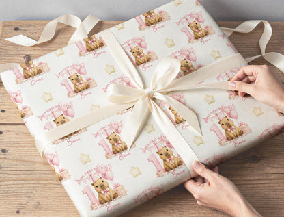 Personalised capybara wrapping paper wrapped around a gift with ribbon, featuring the custom name, pink number one and balloons.