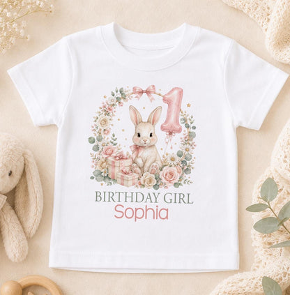 White cotton t-shirt printed with a watercolour bunny in a floral wreath with a number one balloon, with Birthday Girl and a name below.