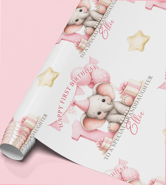 Roll of personalised first birthday wrapping paper featuring a repeating pink baby elephant, number one and balloon design.