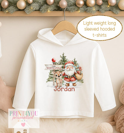 Personalised Christmas hooded t-shirt, white long sleeved hoodie printed with Santa and a reindeer at the North Pole and a name in blue