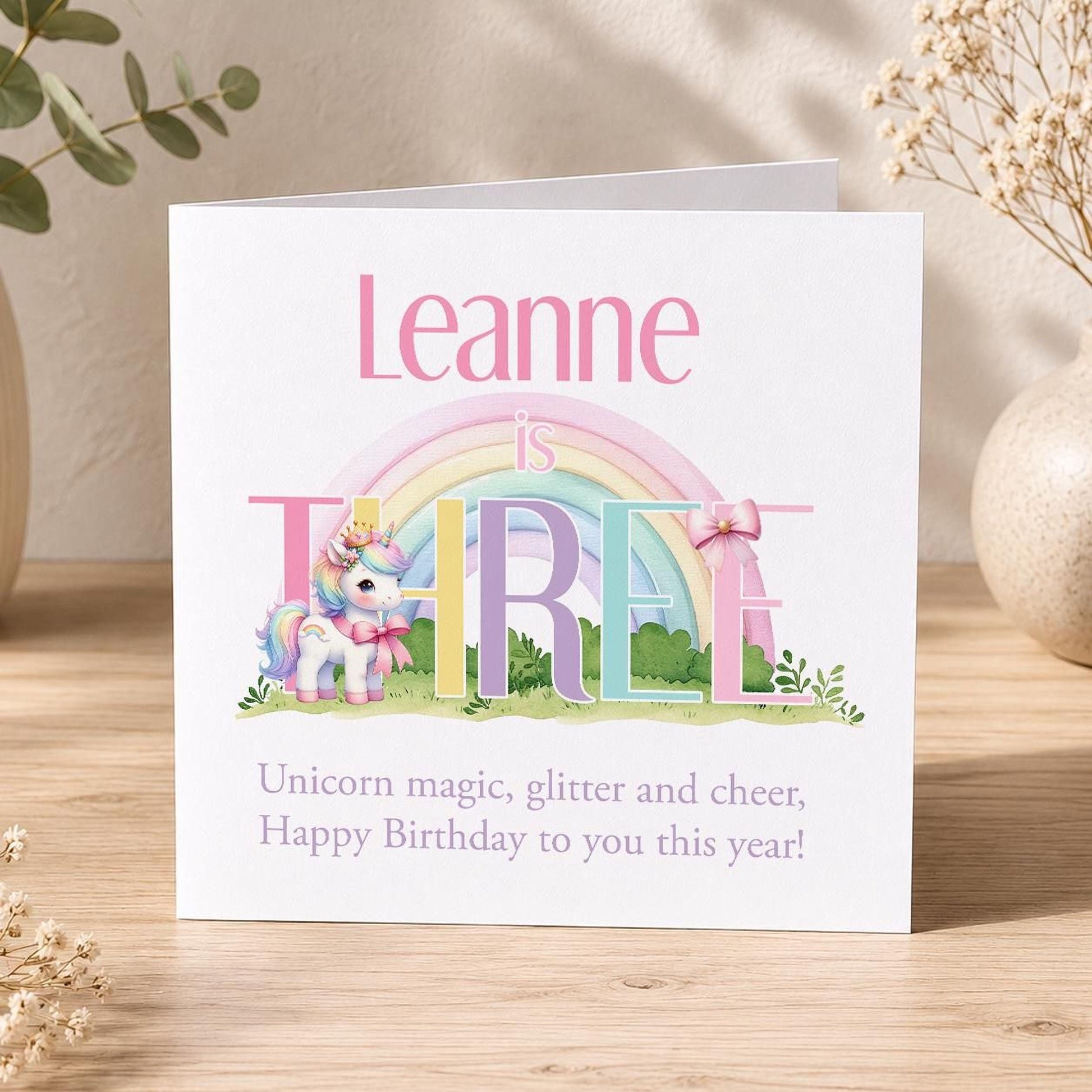Square birthday card featuring a unicorn and rainbow design, personalised with a girl's name and age, for ages 1 to 10.