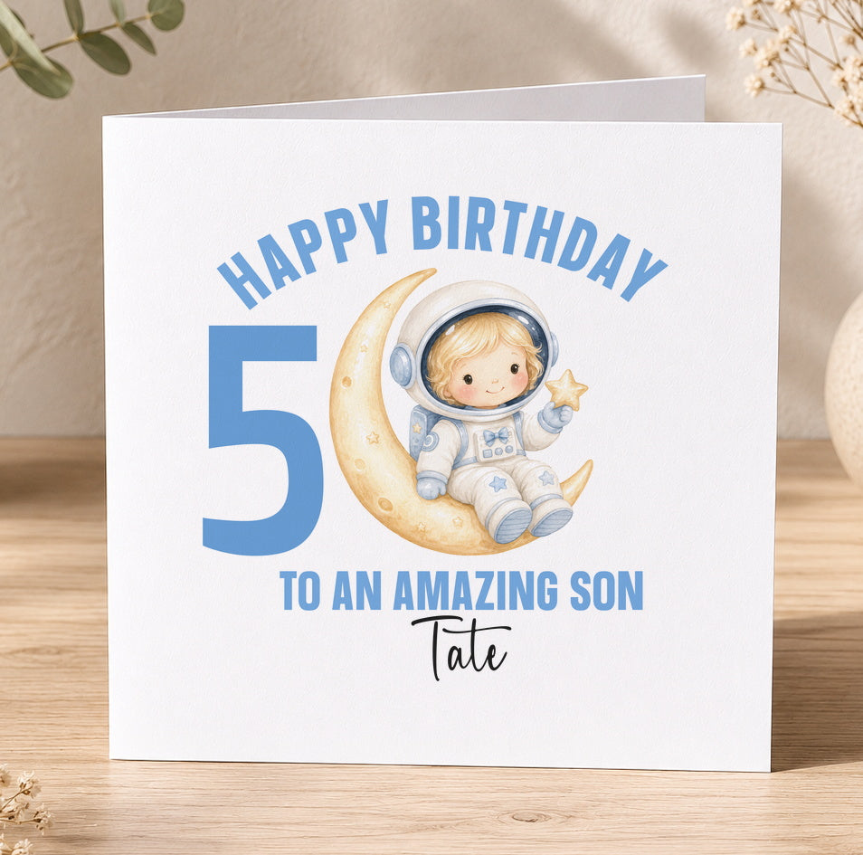 Personalised astronaut birthday card design showing a cartoon spaceman floating on a crescent moon among stars, with space for a child's personalised name and age.