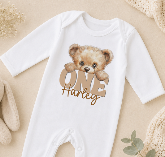 A white onesie with a teddy bear design and the text "ONE Harley" printed on it.