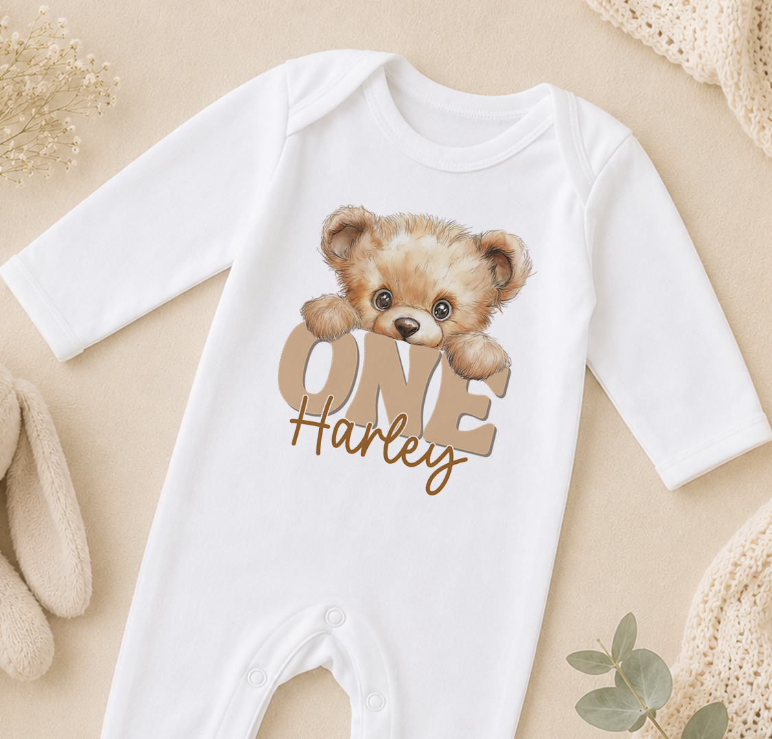 A white onesie with a teddy bear design and the text "ONE Harley" printed on it.
