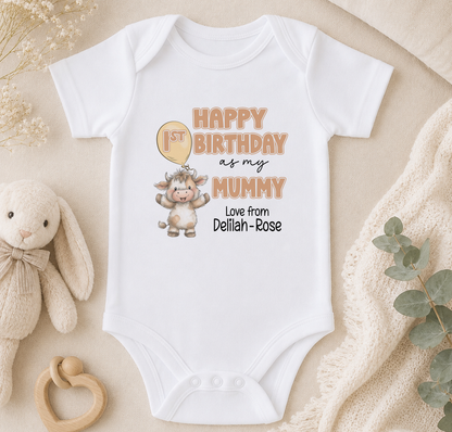 A white baby onesie with a cartoon cow and text that reads "Happy 1st Birthday as my Mummy Love from Delilah-Rose".