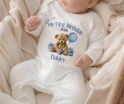 Blue first birthday garment printed with a teddy bear design, laid flat to show the full print.