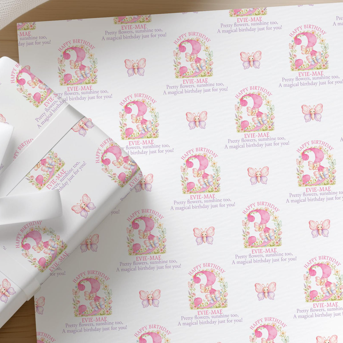 Roll of personalised pink butterfly wrapping paper with an example name and age printed on the design