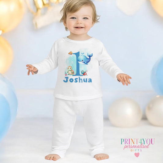 Personalised blue under the sea first birthday pyjamas with your child's name printed on the front, shown in 6-12 months.