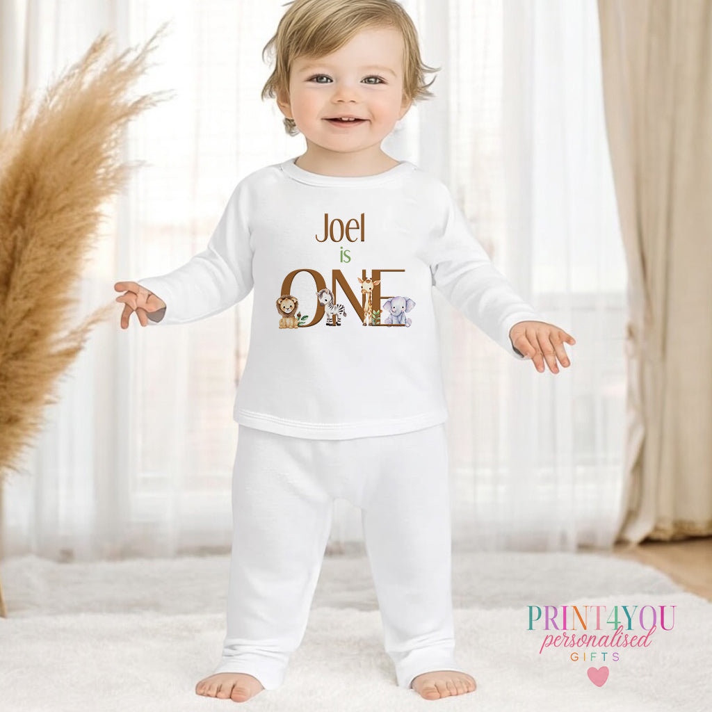 Personalised first birthday pyjamas in white cotton, printed with safari animals and a custom name, 1-2 years size.