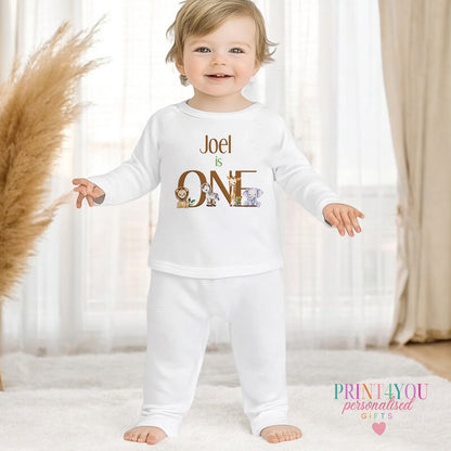 Personalised first birthday pyjamas in white cotton, printed with safari animals and a custom name, 1-2 years size.