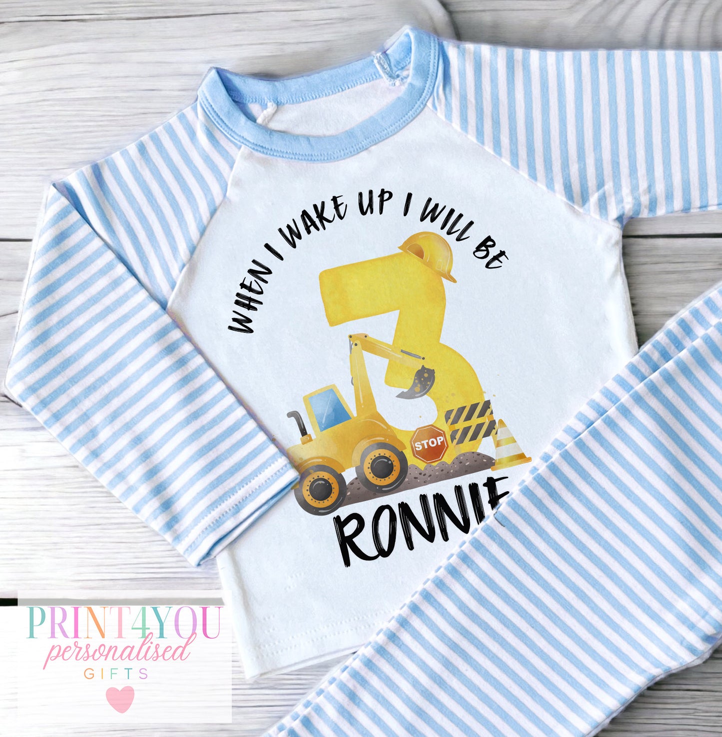 Personalised blue and white striped boys' pyjamas with a construction digger and When I Wake Up countdown numbers 1 to 5 design, personalised with child's name