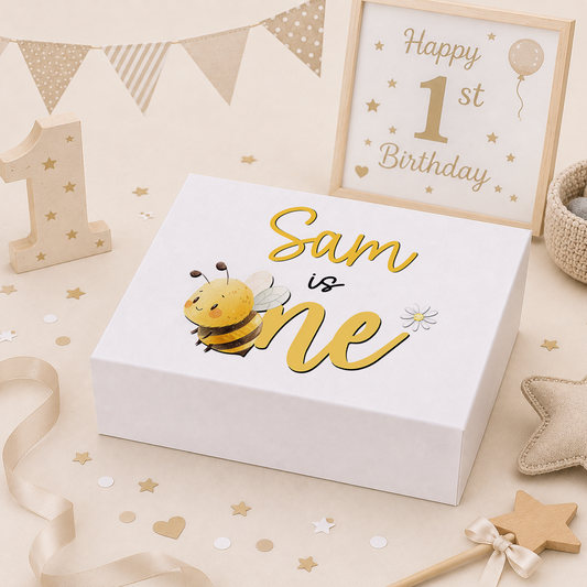 Honey-gold honey bee 1st birthday keepsake box with a magnetic lid, showing a bumble bee, daisy and bunting alongside '[Name] is one' in gold script.