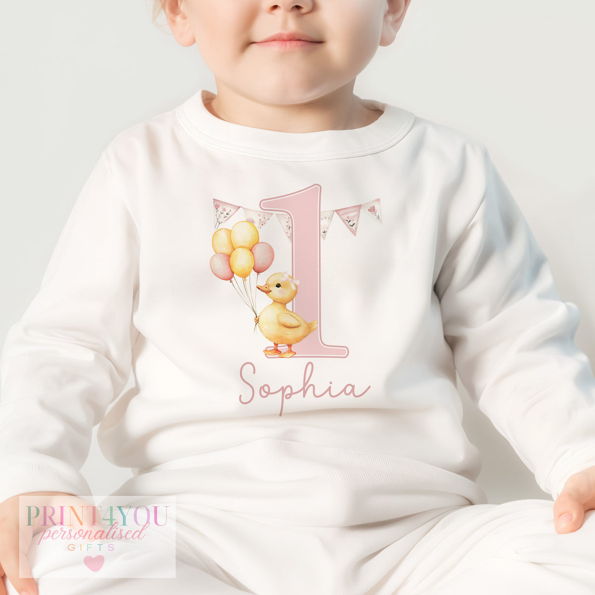 Close-up of the all-over pink duck design personalised with baby's name on first birthday pyjamas.