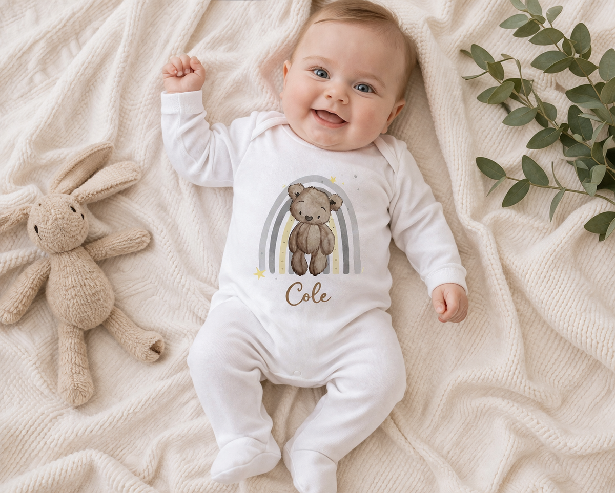 Personalised teddy bear baby vest, custom printed with the baby's name, shown on a soft blanket.