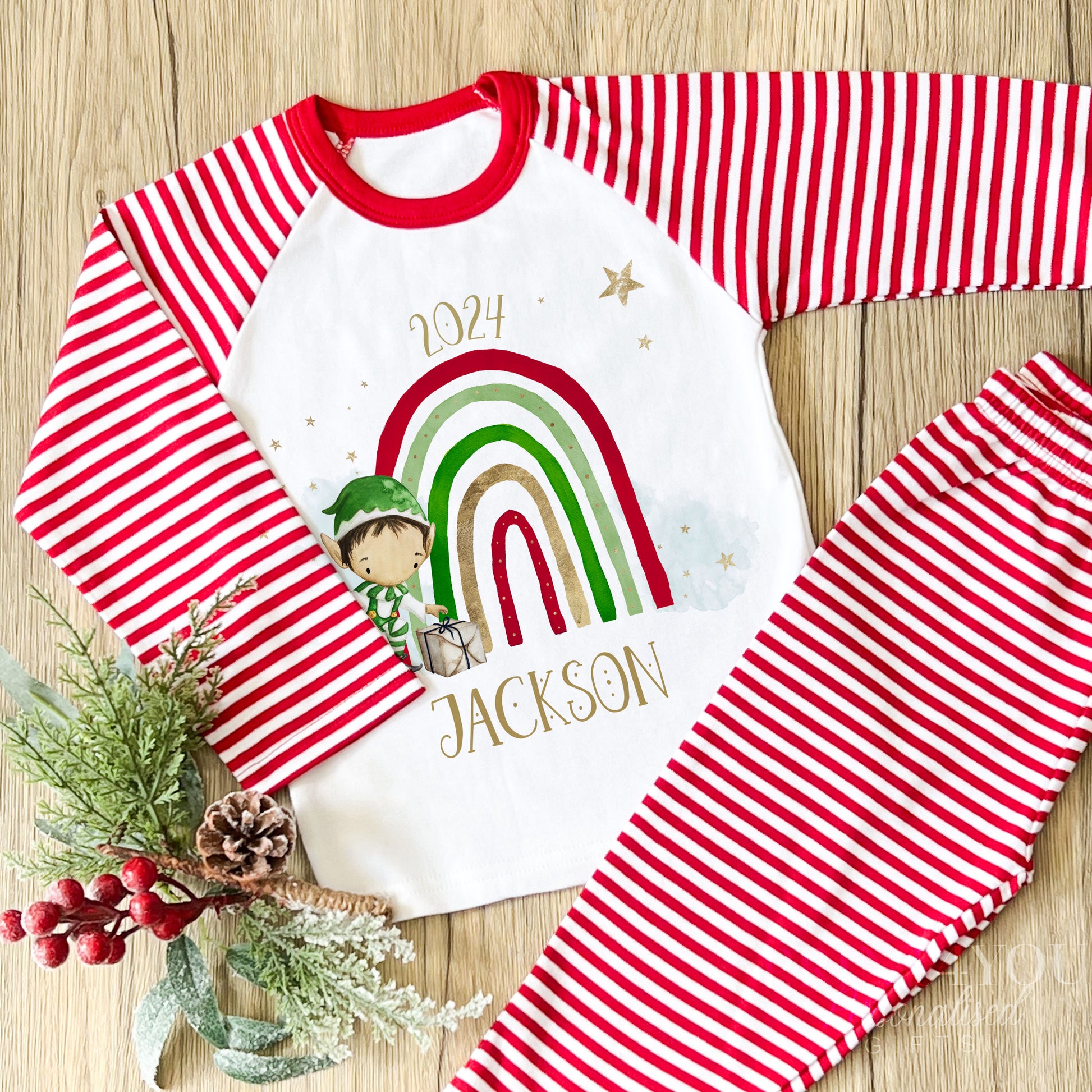 Personalised red and white striped Christmas Eve pyjamas for kids with cheerful Rainbow Elf design and custom name printed on the front