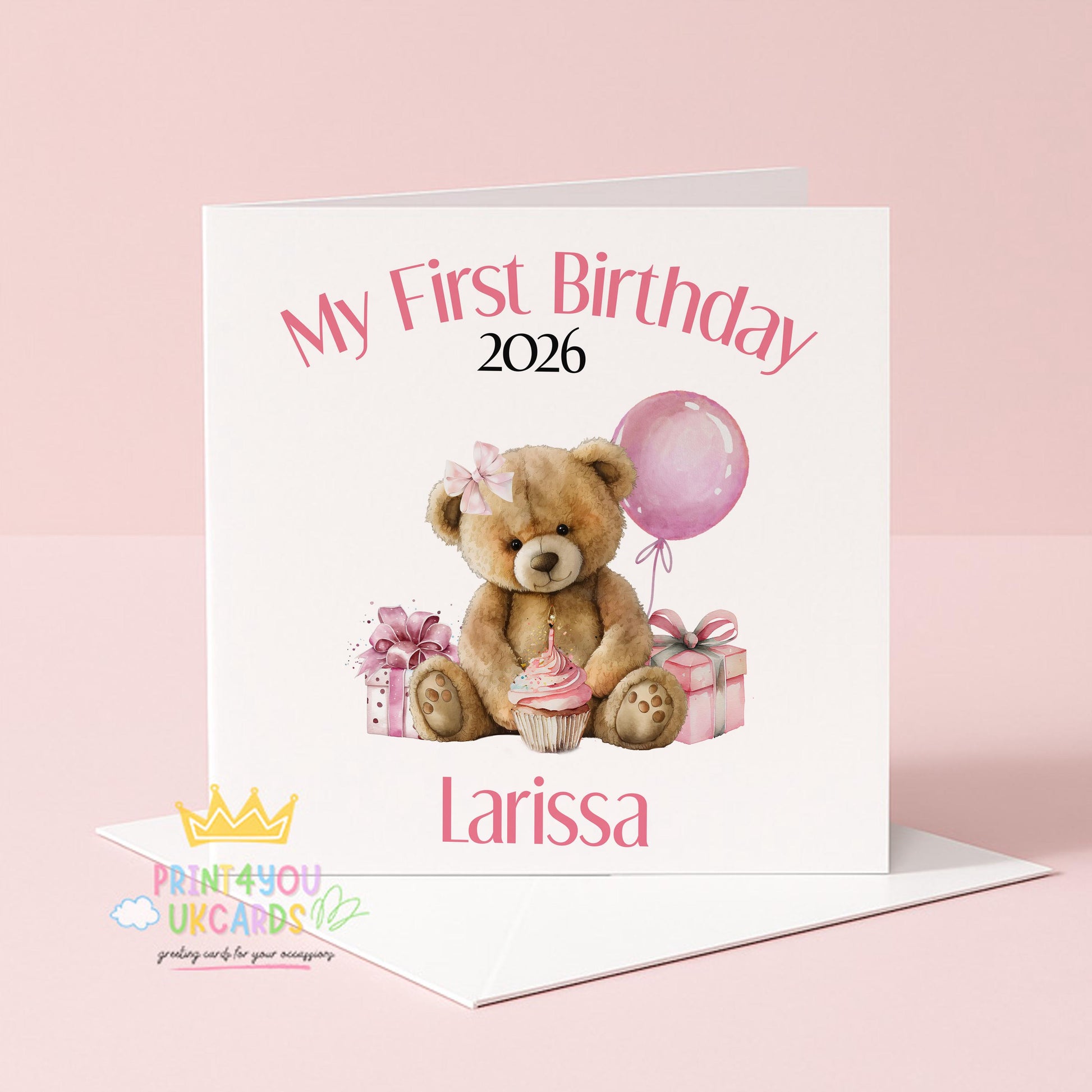 Square pink first birthday card featuring a teddy bear design, shown personalised with a name and year