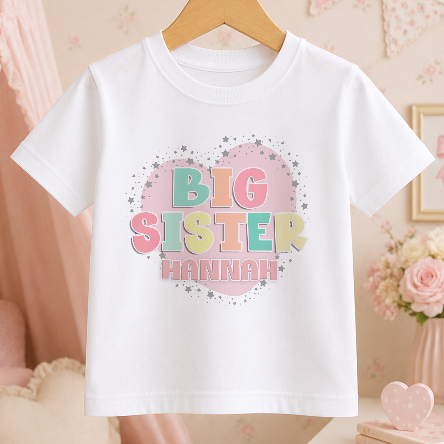 A white t-shirt with a heart-shaped graphic and the text "BIG SISTER HANNAH" printed on it.
