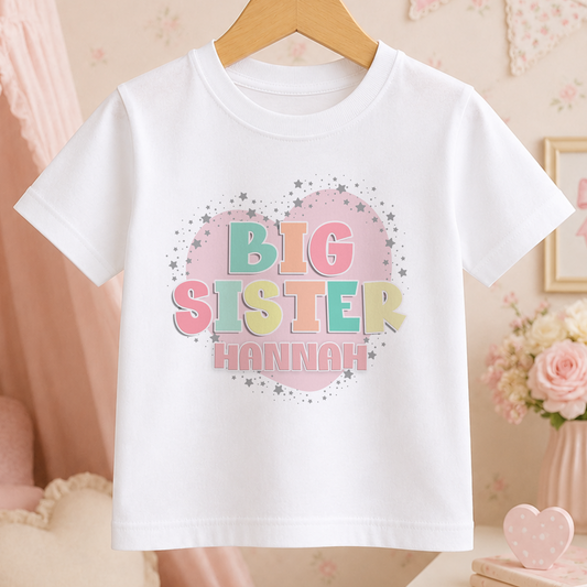 A white t-shirt with a heart-shaped graphic and the text "BIG SISTER HANNAH" printed on it.