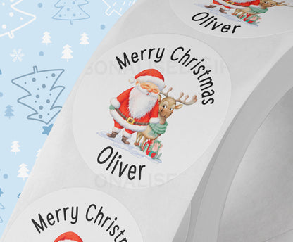Personalised Santa and reindeer Christmas sticker in white gloss finish, printed with a custom name, shown on a strip of 5cm round gift labels