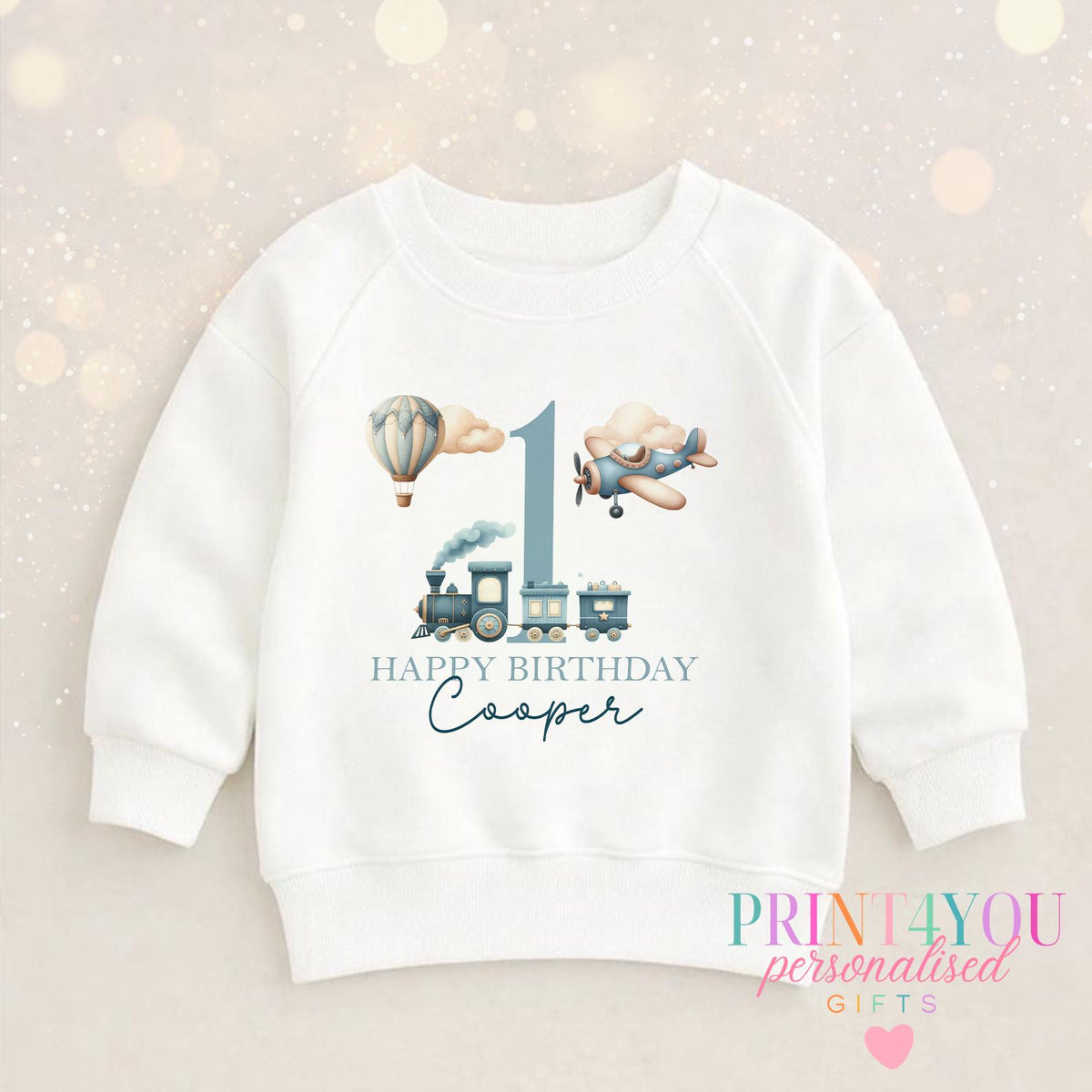Close-up of the vintage transport design personalised with a child's name in flowing script on a first birthday jumper.