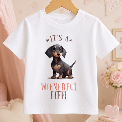 A white t-shirt with a cartoon image of a dachshund dog and the text "It's a Wienerful Life!" printed on it.