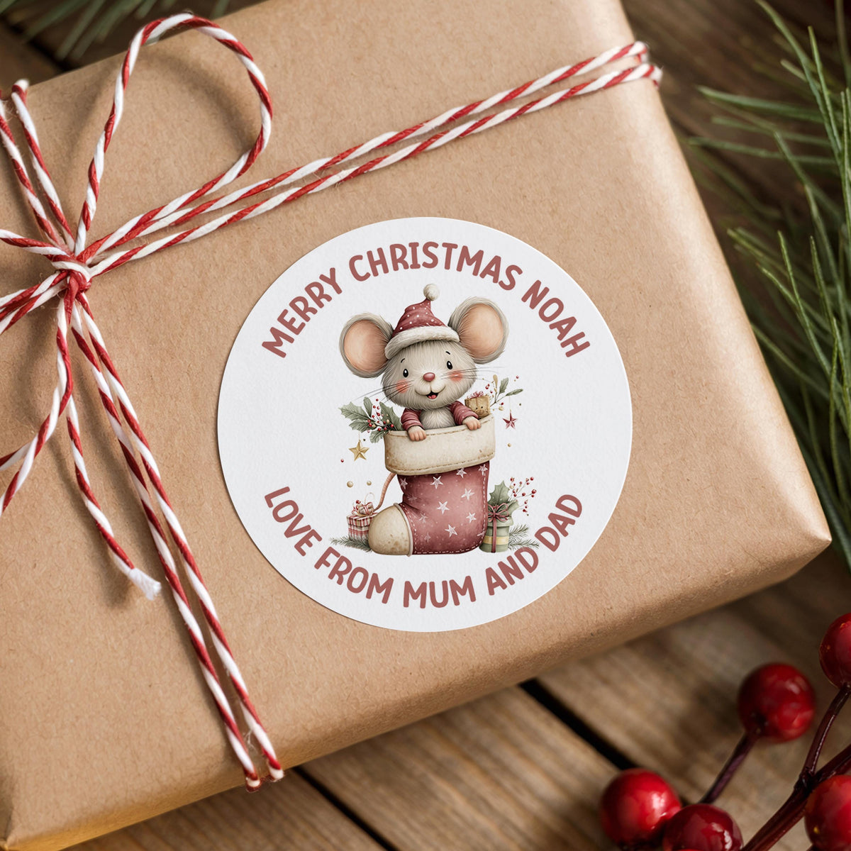 Personalised Christmas mouse sticker with custom name on a wrapped gift box with festive berries and decorations