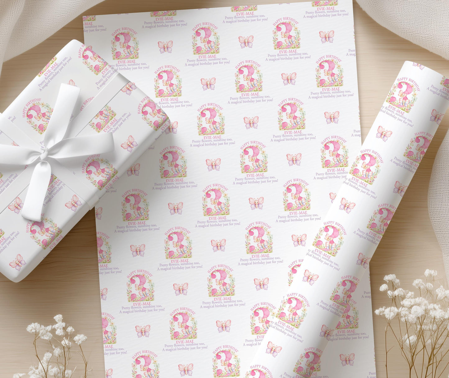 Close-up of the personalised pink butterfly wrapping paper with a floral age number and custom name