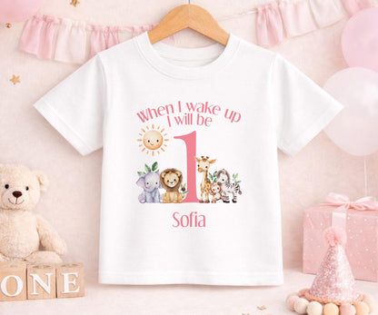 Baby girl wearing a personalised pink safari first birthday outfit with a custom name printed on soft cotton.