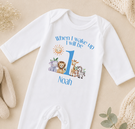 A white onesie with a personalized text and animal illustrations, specifically featuring a sun and a lion, is displayed on a beige surface.