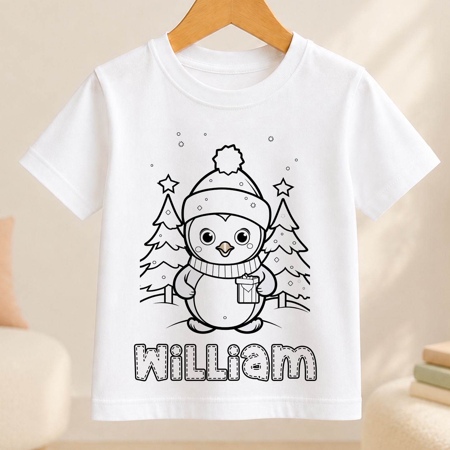 A white t-shirt with a black and white illustration of a penguin wearing a hat and scarf, surrounded by snow and trees. The name "William" is written below the illustration.