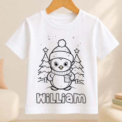 A white t-shirt with a black and white illustration of a penguin wearing a hat and scarf, surrounded by snow and trees. The name "William" is written below the illustration.