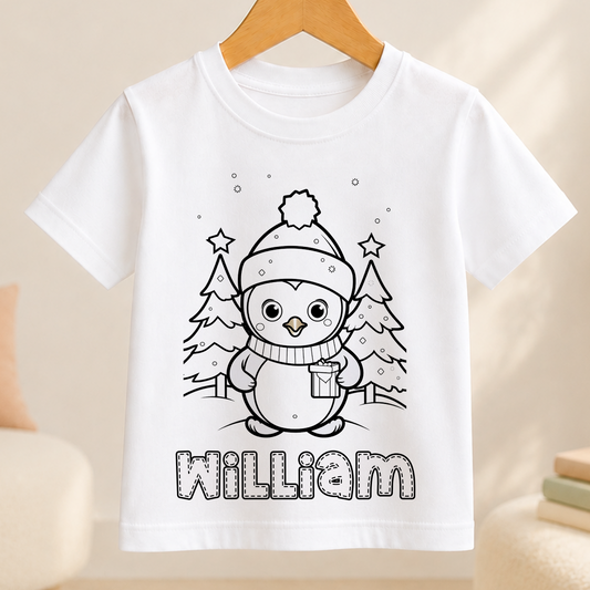 A white t-shirt with a black and white illustration of a penguin wearing a hat and scarf, surrounded by snow and trees. The name "William" is written below the illustration.