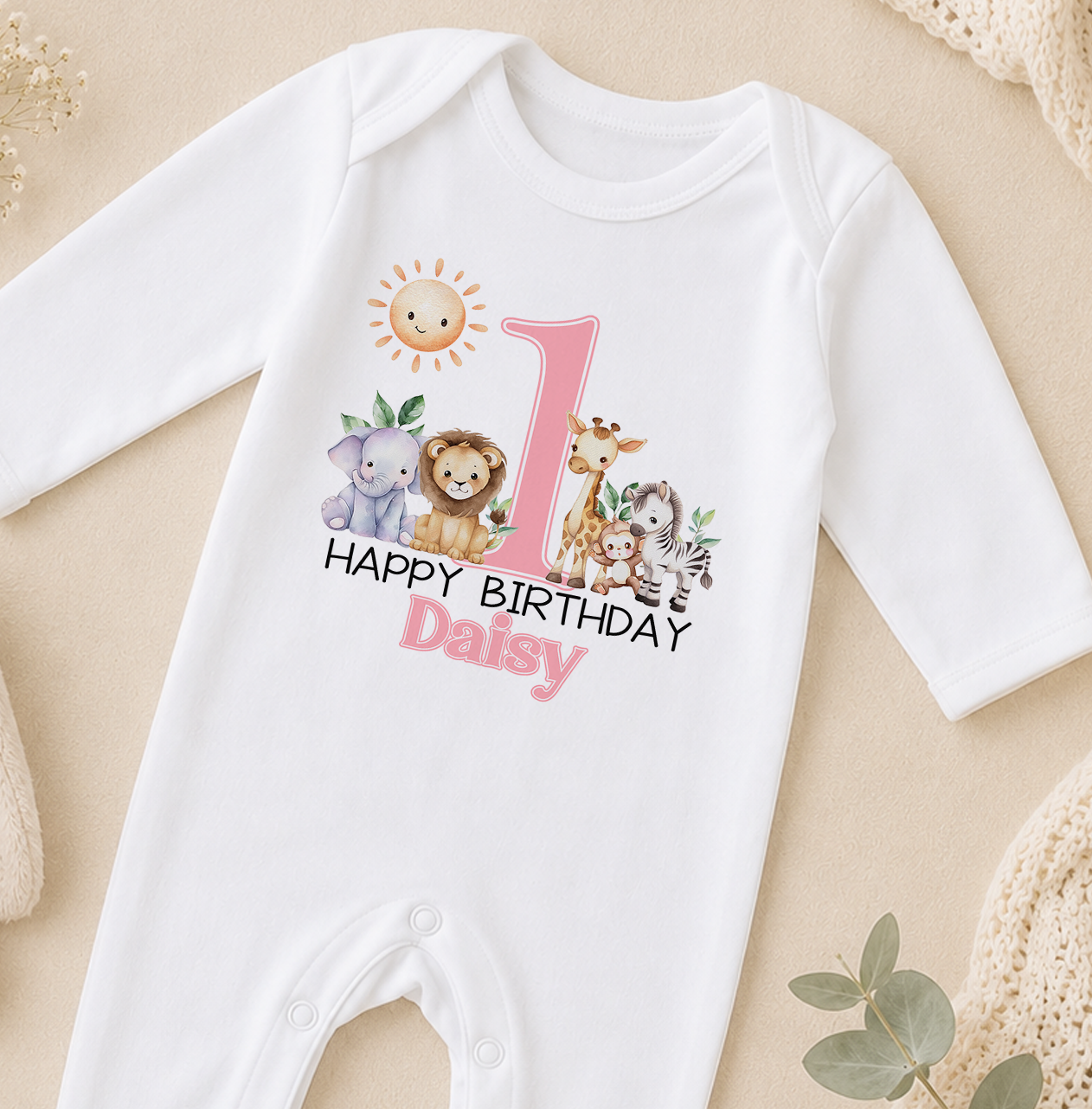 A white onesie with a pink number 1 and a design of various animals, including a lion, giraffe, and zebra, along with the text "Happy Birthday Daisy".