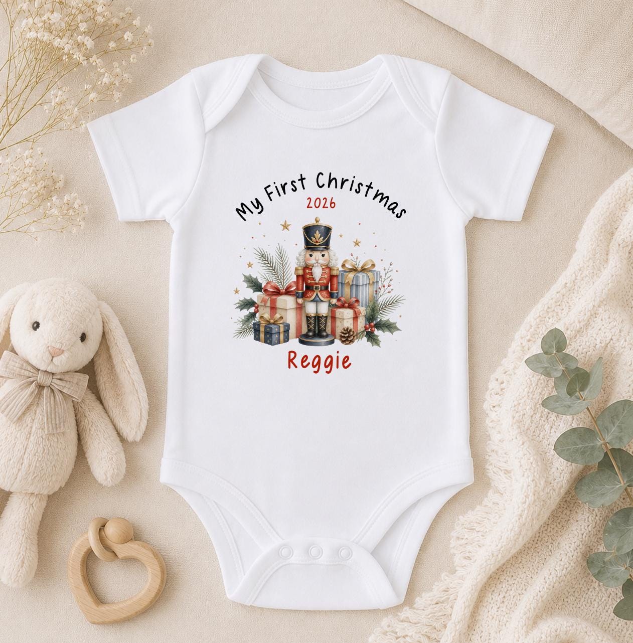 Personalised baby first Christmas short sleeved vest in white cotton printed with a nutcracker design and baby's name