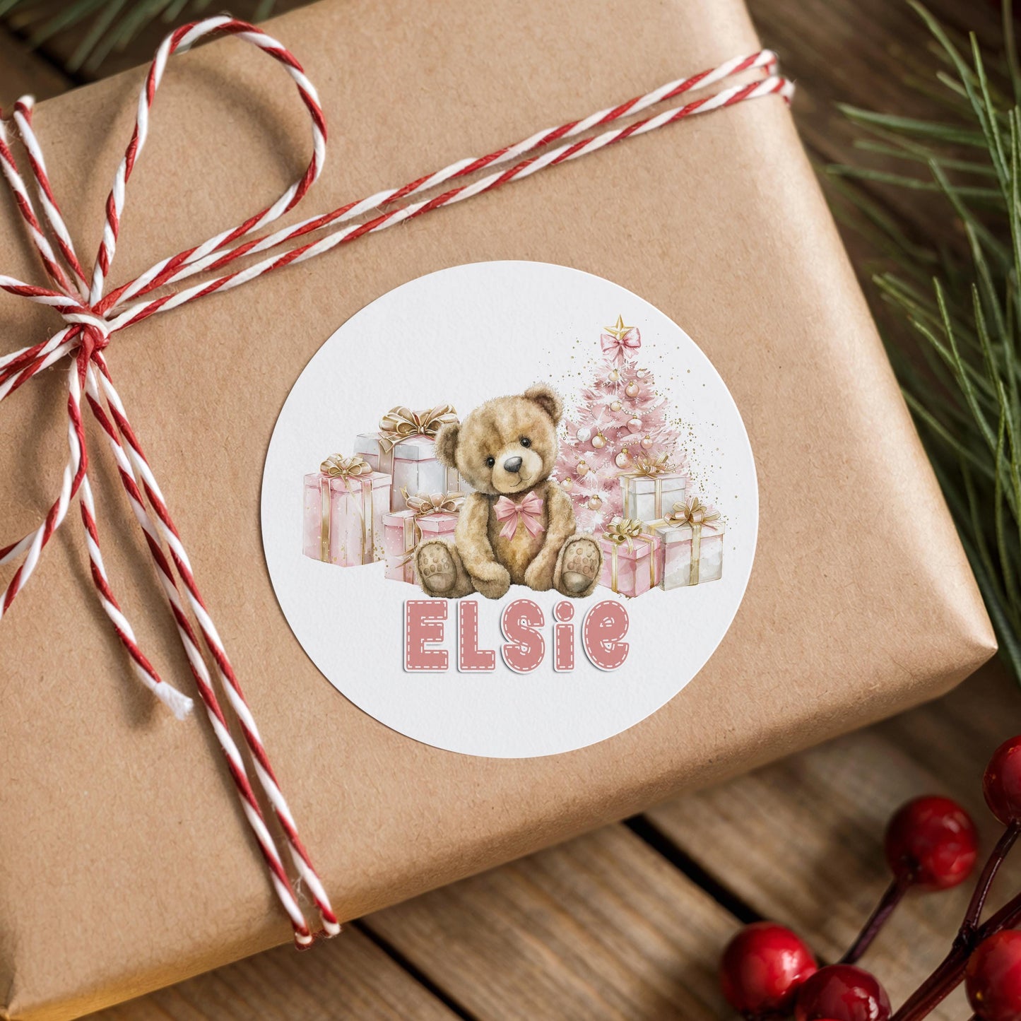 Gift box wrapped in red and white ribbon finished with a personalised pastel pink teddy bear Christmas sticker printed with a custom name