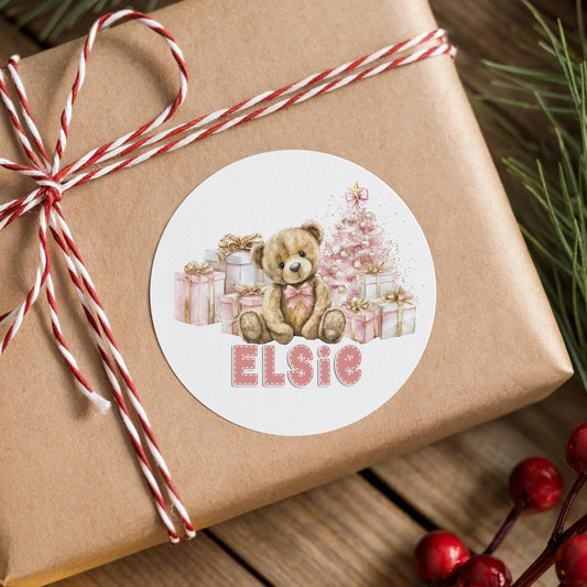 Gift box wrapped in red and white ribbon finished with a personalised pastel pink teddy bear Christmas sticker printed with a custom name