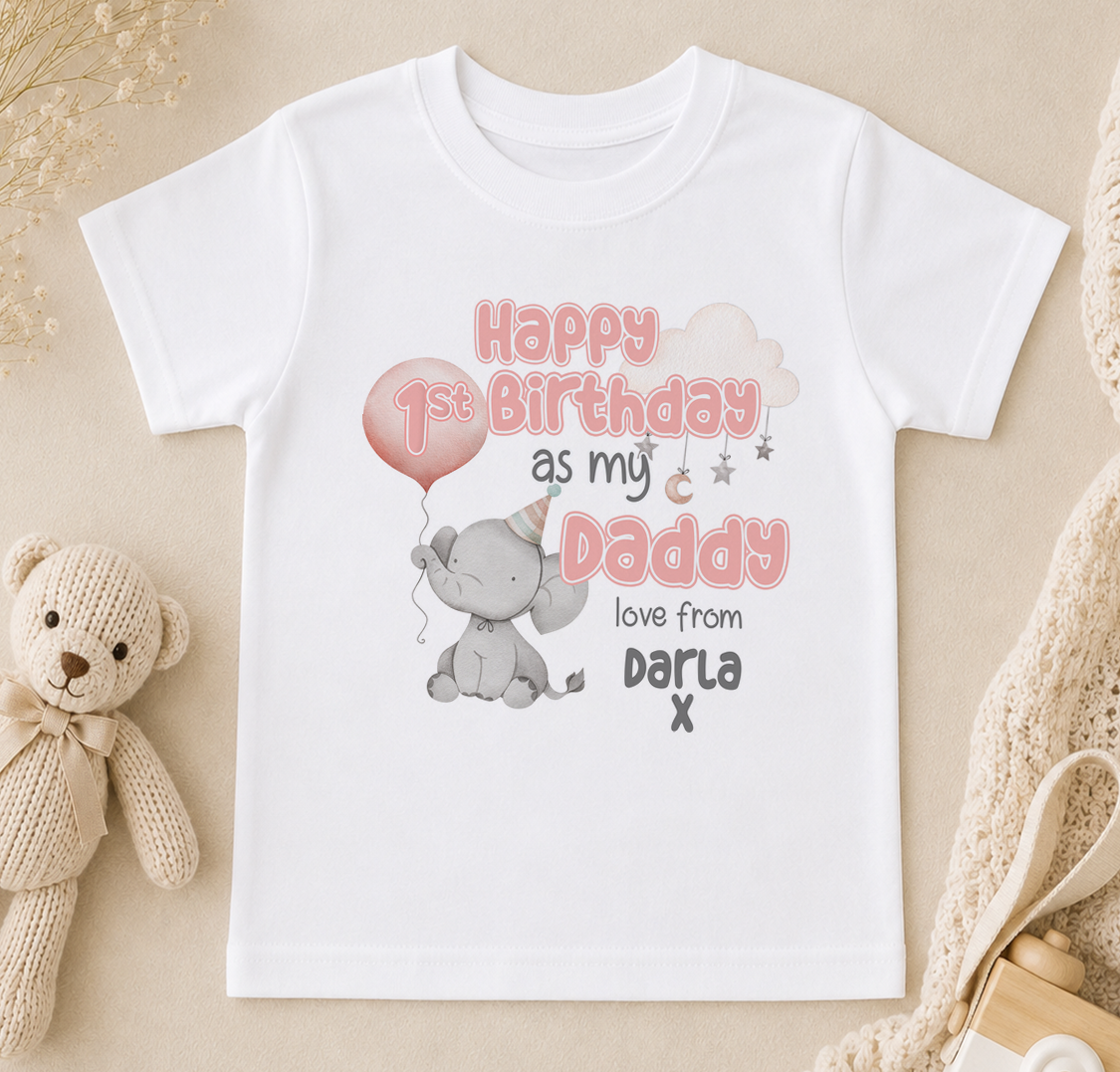 A white t-shirt with a birthday message printed on it, featuring a cute elephant and a balloon, along with the text "Happy 1st Birthday as my Daddy loves from Dara X".
