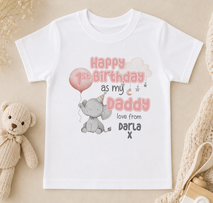 A white t-shirt with a birthday message printed on it, featuring a cute elephant and a balloon, along with the text "Happy 1st Birthday as my Daddy loves from Dara X".