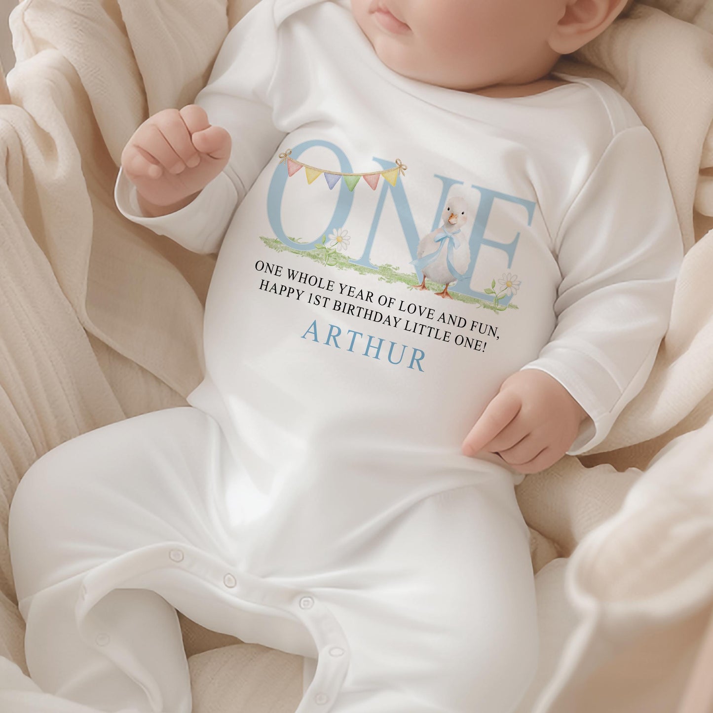 Personalised first birthday sleepsuit with blue duck design and custom name print.
