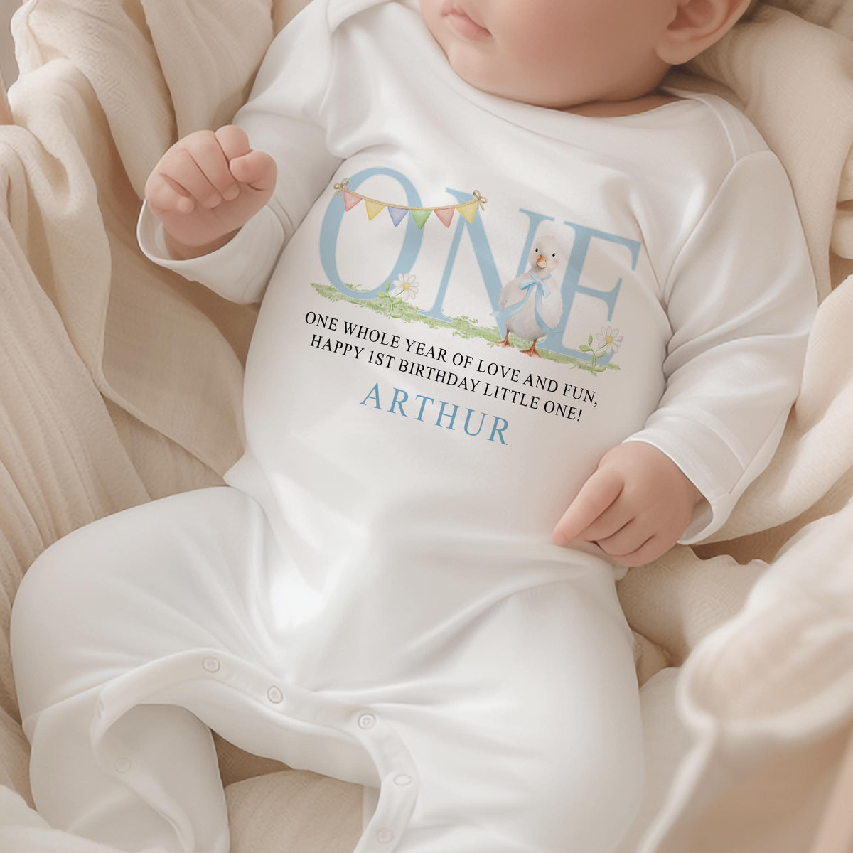 Personalised first birthday sleepsuit with blue duck design and custom name print.