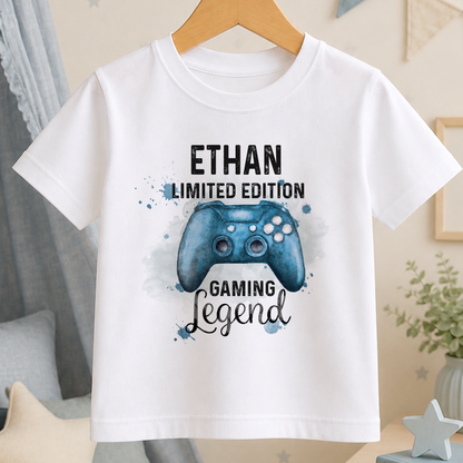 A white t-shirt with a graphic design featuring a blue gaming controller and the text "ETHAN LIMITED EDITION GAMING LEGEND".