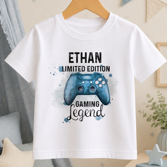 A white t-shirt with a graphic design featuring a blue gaming controller and the text "ETHAN LIMITED EDITION GAMING LEGEND".