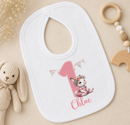 A white bib with a pink bunny and the name "Chloe" printed on it, along with a bib number and a bib number holder.