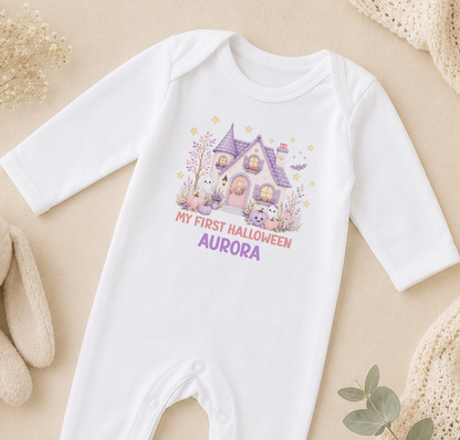 A white onesie with a Halloween-themed graphic and text, laid out on a beige surface.