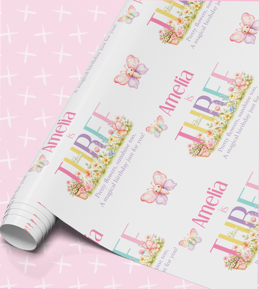 The image is a roll of wrapping paper with a repeating pattern of butterflies and flowers, along with the name "Amelia" printed on it.
