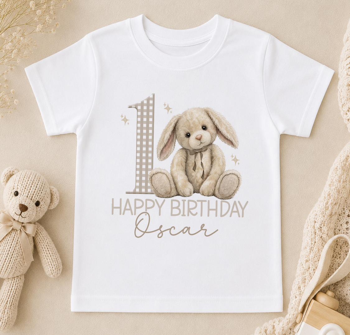 A white t-shirt with a graphic design featuring a teddy bear and the number 1, along with the text "Happy Birthday Oscar".