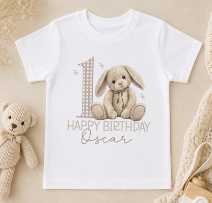 A white t-shirt with a graphic design featuring a teddy bear and the number 1, along with the text "Happy Birthday Oscar".